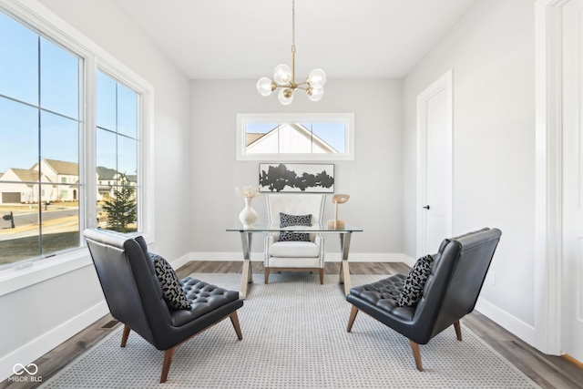 living area featuring a notable chandelier, baseboards, and wood finished floors