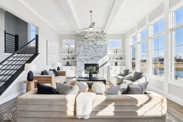 living area with stairs, a fireplace, wood finished floors, and beam ceiling