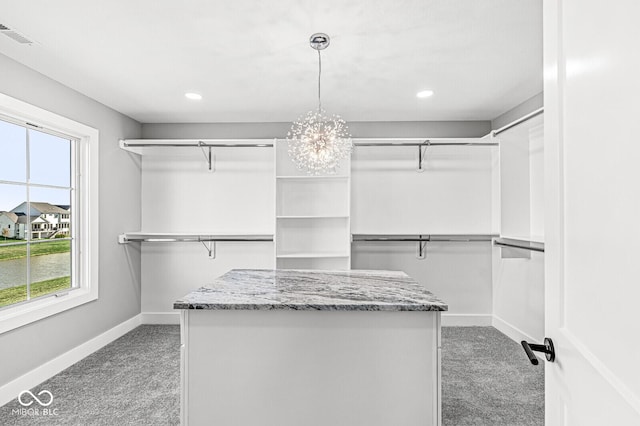 walk in closet with light carpet, visible vents, and an inviting chandelier