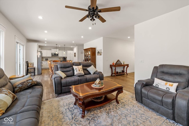 living room with a ceiling fan, recessed lighting, baseboards, and light wood finished floors