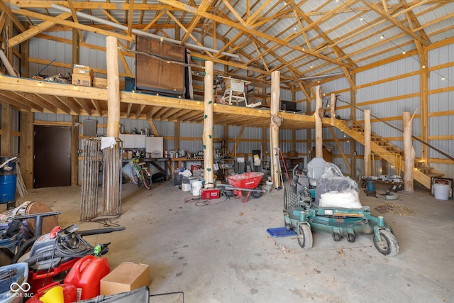 miscellaneous room featuring concrete floors, metal wall, and lofted ceiling