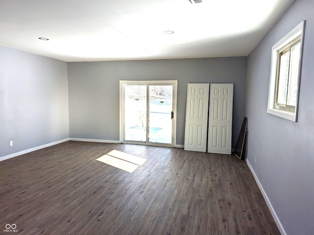 spare room with dark wood-type flooring, recessed lighting, and baseboards