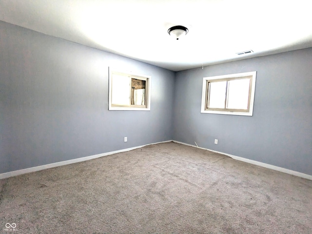 unfurnished room with carpet, visible vents, and baseboards