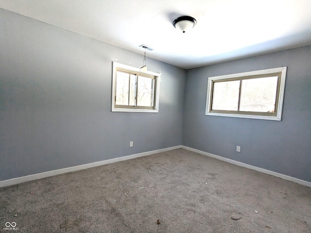 spare room featuring carpet flooring, visible vents, and baseboards