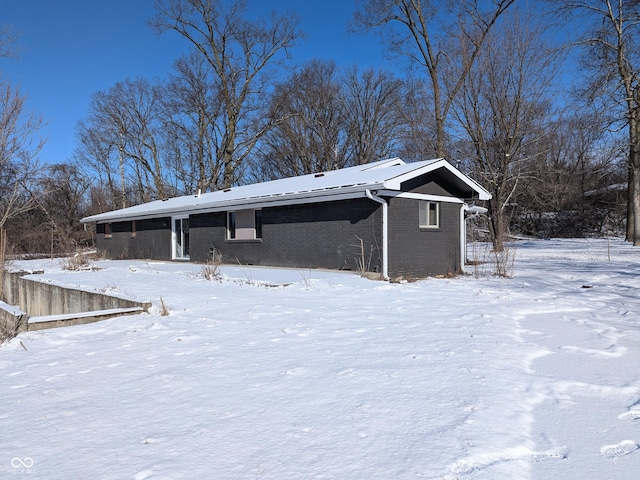 snow covered rear of property with brick siding