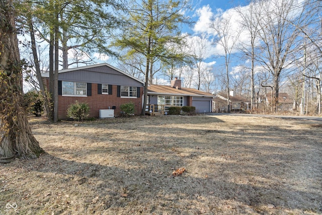 tri-level home with a garage, brick siding, and a chimney