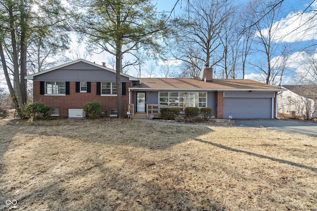 view of front facade with aphalt driveway, an attached garage, brick siding, a chimney, and a front yard