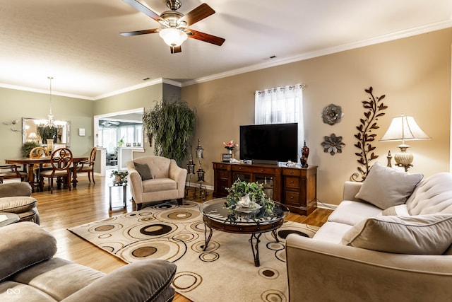 living area featuring ceiling fan with notable chandelier, ornamental molding, wood finished floors, and baseboards