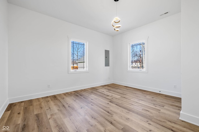 spare room with light wood-style flooring, electric panel, and a healthy amount of sunlight