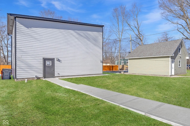 view of side of property with an outbuilding, a lawn, and fence