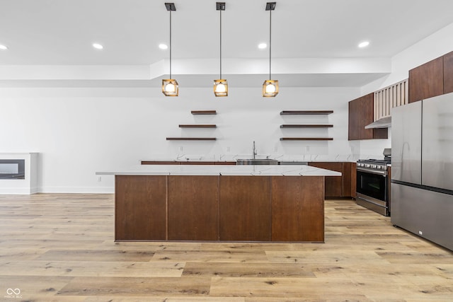 kitchen with modern cabinets, appliances with stainless steel finishes, decorative light fixtures, under cabinet range hood, and open shelves