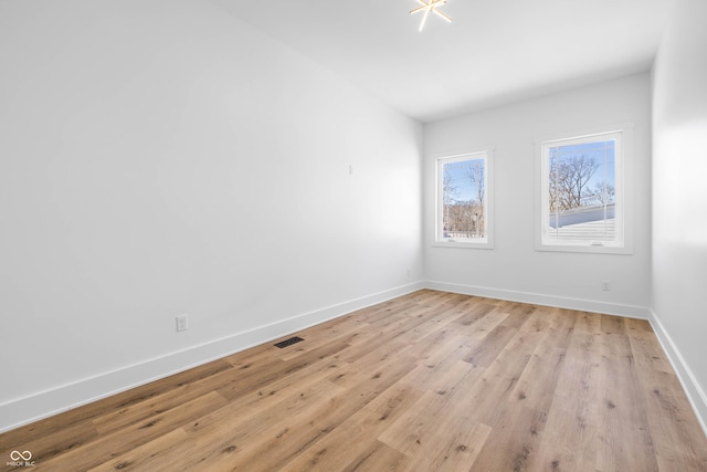 spare room with light wood-style flooring, visible vents, and baseboards