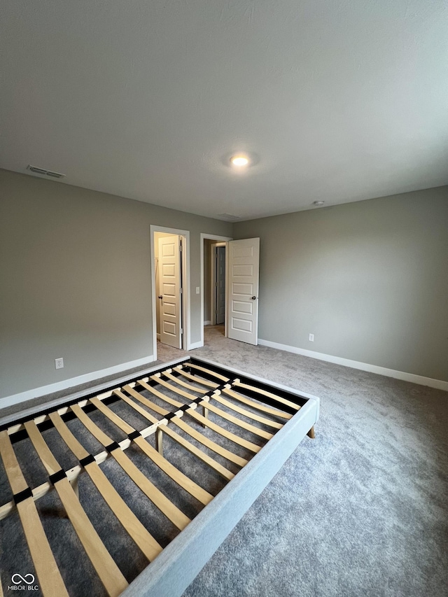 empty room featuring carpet floors, visible vents, and baseboards