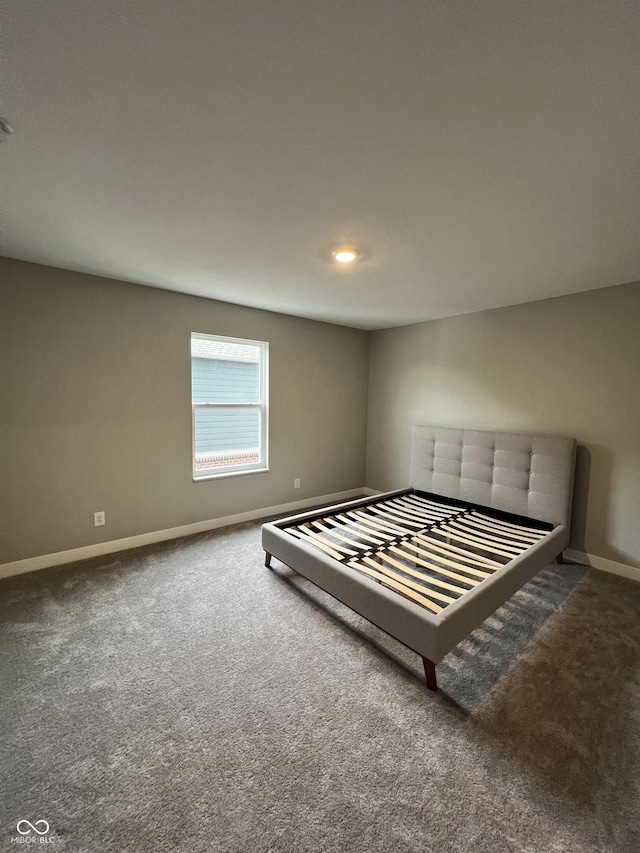 unfurnished bedroom featuring dark carpet and baseboards