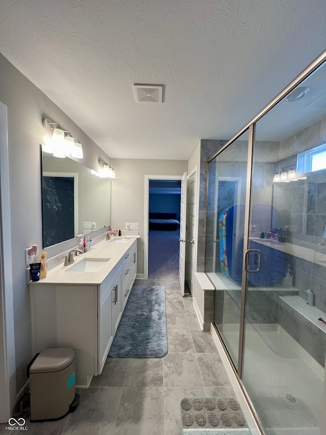 full bathroom with double vanity, a shower stall, visible vents, and a sink