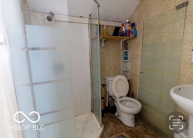 full bath featuring toilet, a stall shower, and tile walls