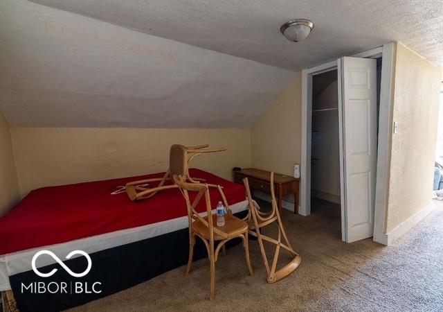 bedroom with lofted ceiling, carpet flooring, a textured ceiling, and baseboards