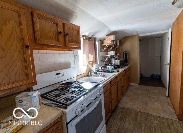 kitchen with white range with gas cooktop and brown cabinets