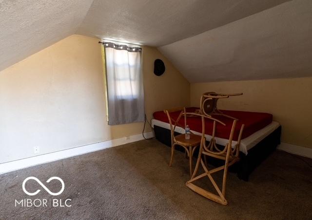 bedroom featuring lofted ceiling, carpet, a textured ceiling, and baseboards