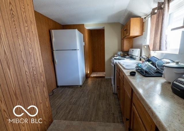 kitchen with white appliances, wood walls, light countertops, brown cabinets, and dark wood finished floors