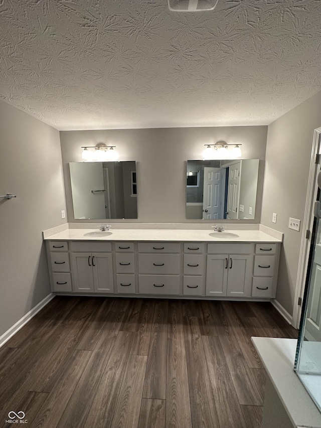 full bathroom with double vanity, a sink, and wood finished floors