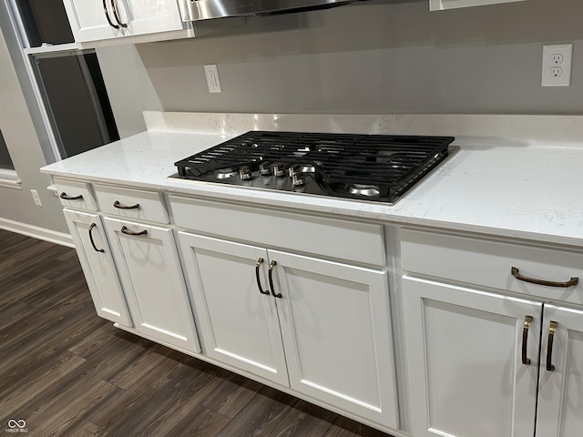 kitchen with white cabinetry, stainless steel gas stovetop, light stone counters, and dark wood-style flooring