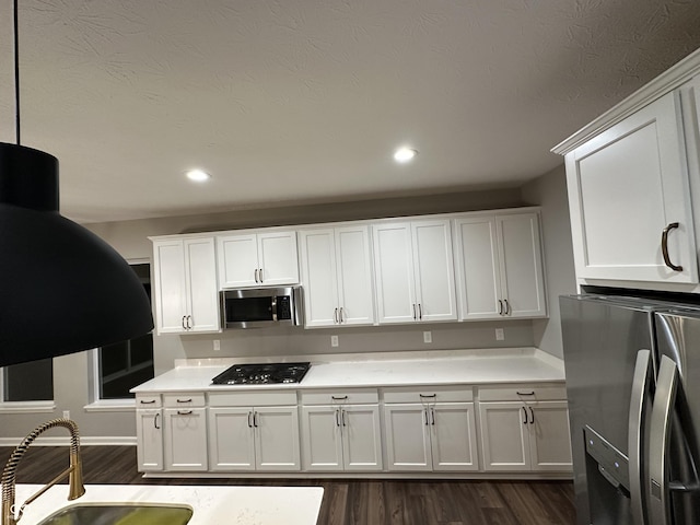 kitchen featuring light countertops, appliances with stainless steel finishes, dark wood-style flooring, and white cabinets