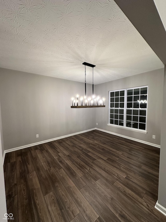 spare room with dark wood-style flooring, a textured ceiling, and baseboards