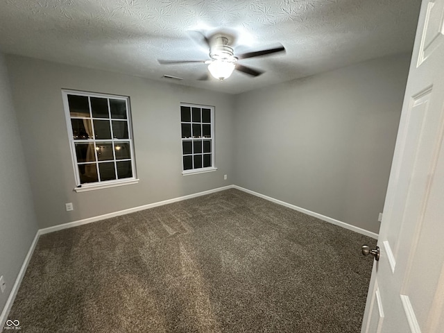 carpeted spare room with a ceiling fan, visible vents, a textured ceiling, and baseboards