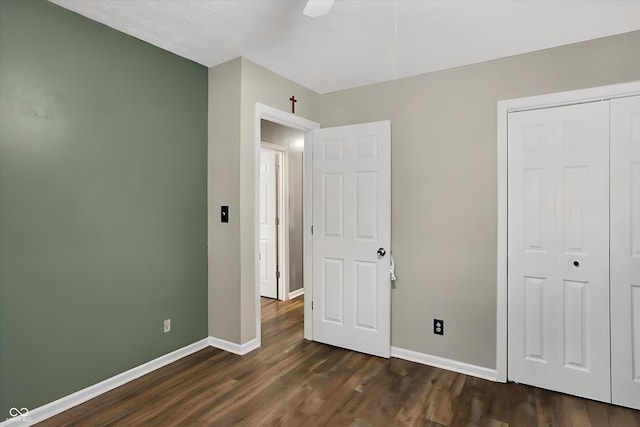 unfurnished bedroom with a ceiling fan, a closet, baseboards, and dark wood-style flooring