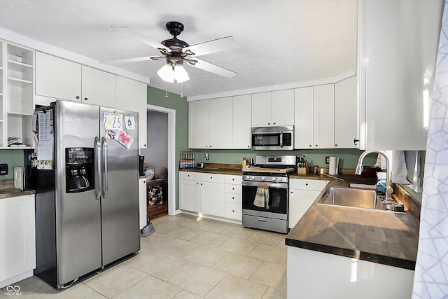 kitchen with dark countertops, white cabinetry, appliances with stainless steel finishes, and a sink