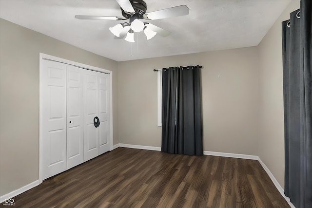 unfurnished bedroom with dark wood-style floors, a closet, and baseboards