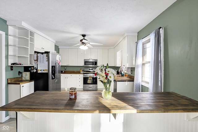 kitchen with butcher block counters, a sink, white cabinetry, appliances with stainless steel finishes, and open shelves