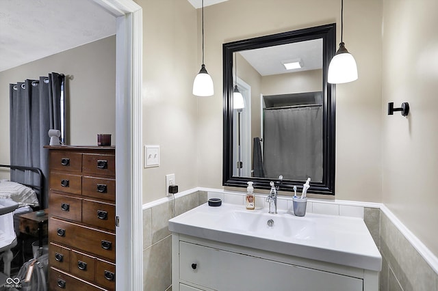 bathroom featuring a wainscoted wall, tile walls, and vanity