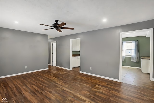 unfurnished bedroom with connected bathroom, baseboards, and dark wood-style flooring