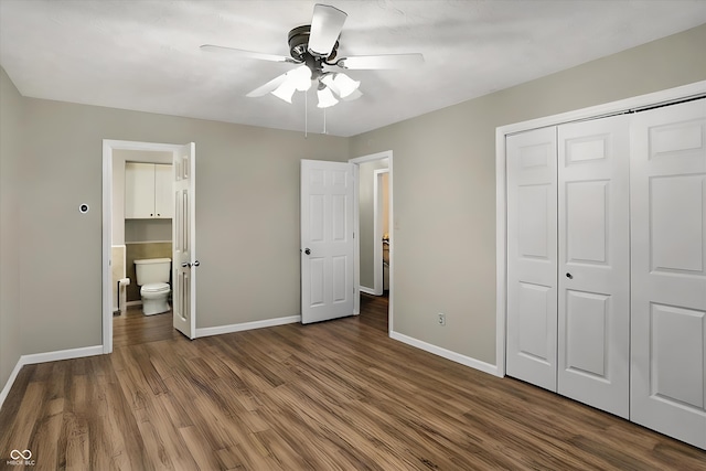 unfurnished bedroom with baseboards, a ceiling fan, dark wood-type flooring, ensuite bathroom, and a closet