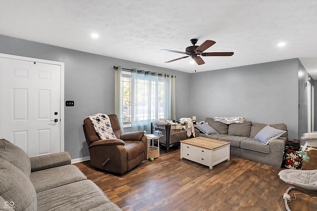 living area featuring a ceiling fan, dark wood finished floors, a textured ceiling, and baseboards