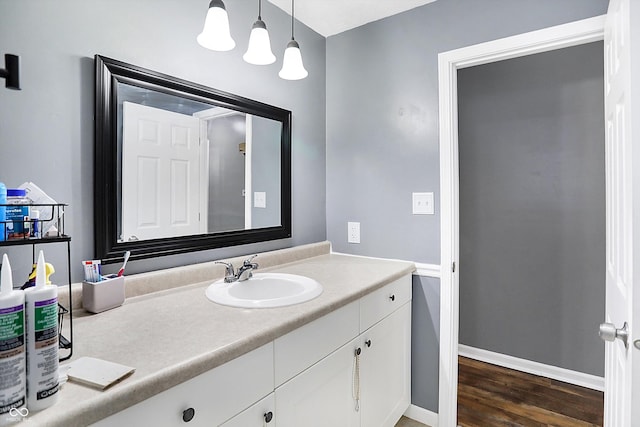 bathroom with wood finished floors, vanity, and baseboards