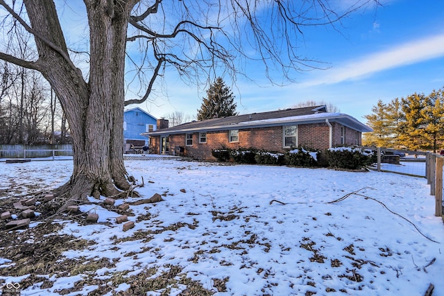 exterior space featuring brick siding, fence, and a chimney