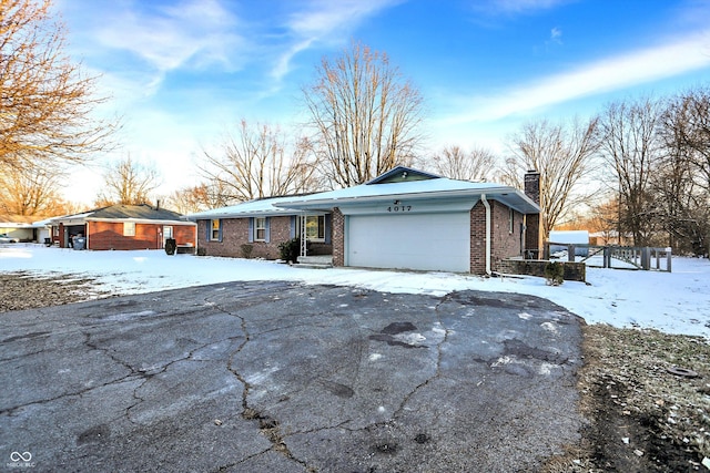 view of front facade featuring an attached garage, driveway, a chimney, and brick siding