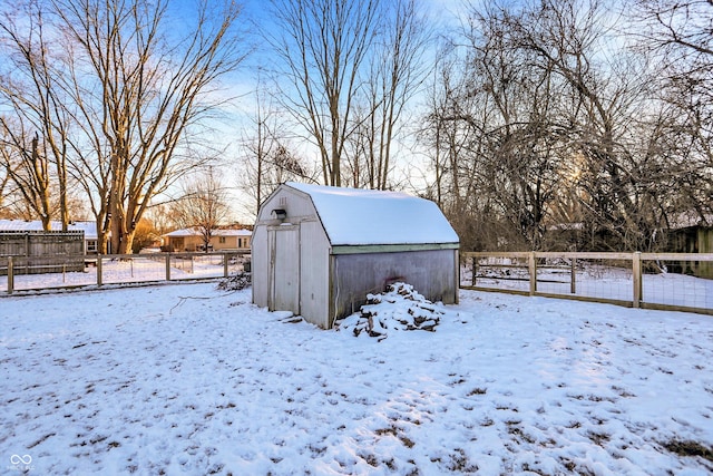 snow covered structure featuring fence and an outdoor structure