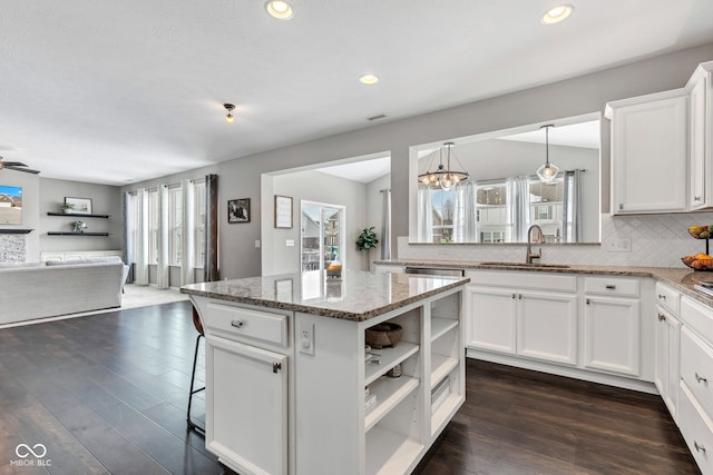 kitchen with white cabinets, a kitchen island, hanging light fixtures, light stone countertops, and open shelves