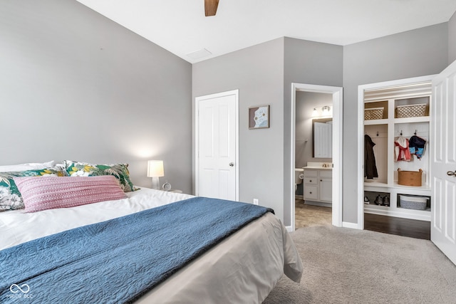 carpeted bedroom featuring ceiling fan, ensuite bath, and baseboards