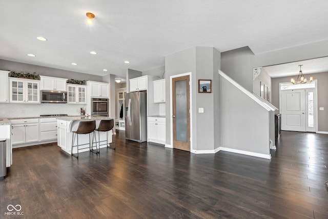 kitchen with white cabinets, glass insert cabinets, a breakfast bar, a center island, and stainless steel appliances