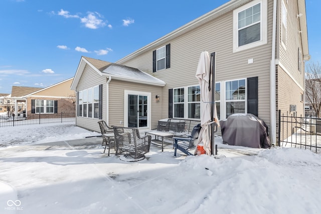 snow covered rear of property with brick siding and fence