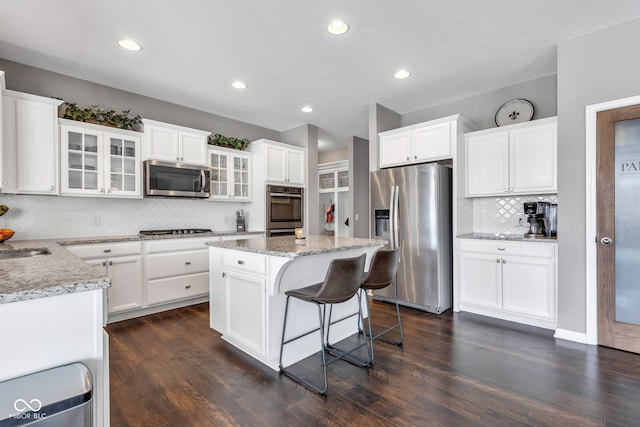 kitchen featuring glass insert cabinets, white cabinetry, a kitchen island, and appliances with stainless steel finishes