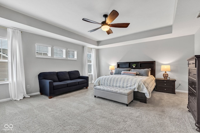 bedroom featuring ceiling fan, baseboards, a raised ceiling, and light colored carpet