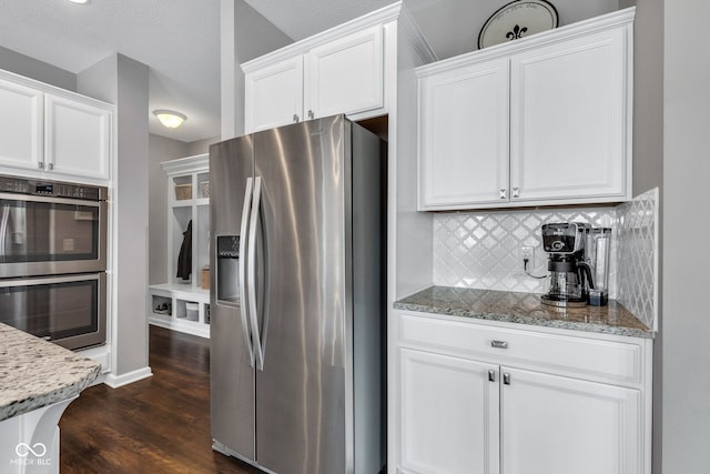 kitchen featuring white cabinets, light stone counters, stainless steel appliances, and backsplash