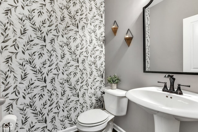 half bathroom featuring baseboards, a sink, and toilet