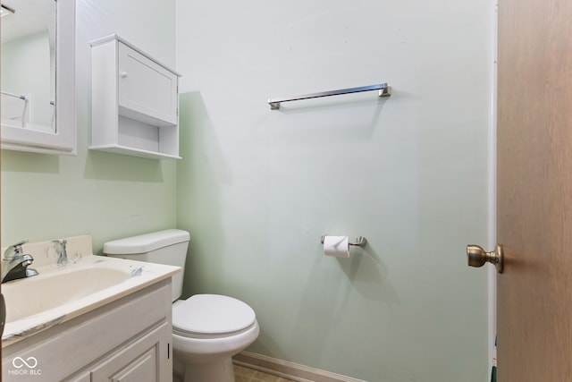 half bath featuring baseboards, vanity, and toilet